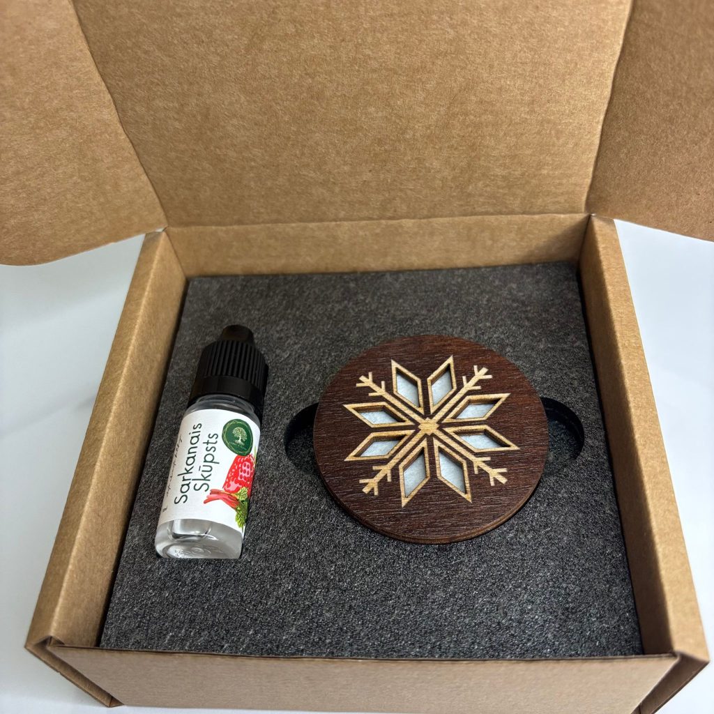 Ventilācijas restītē iespraužams tumša koka auto atsvaidzinātājs ar sniegpārslas motīvu un aromātu "Sarkanais skūpsts".